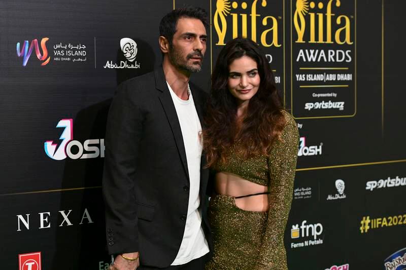 Arjun Rampal in a relaxed blazer over a white T-shirt alongside Gabriella Demetriades, who is wearing a golden two-piece with a cropped top. Khushnum Bhandari / The National
