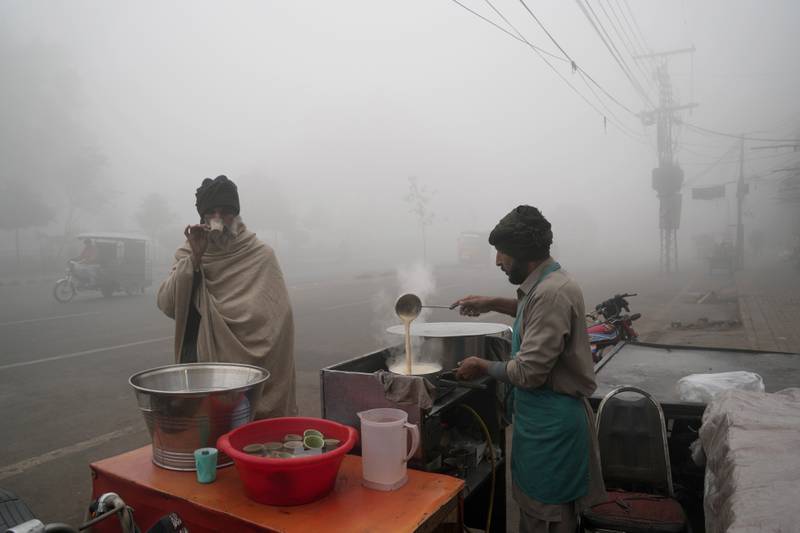 A man drinks tea at a roadside stall as heavy fog reduces visibility in Lahore, Pakistan. AP