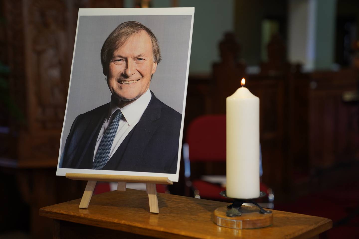 A candle and a photo of MP Sir David Amess at a vigil at St Michael’s and All Angels church in Leigh-on-Sea, Essex. The politician was stabbed to death at a constituency surgery in the town. PA