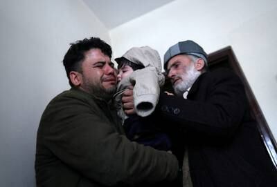 Hamid Safi, a taxi driver who found Sohail Ahmadi at Kabul airport, cries as he hands the child to Sohail's grandfather Mohammad Qasem Razawi. Reuters