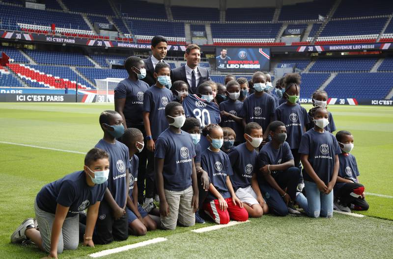 Lionel Messi and president of PSG Nasser Al-Khelaifi pose with children on the pitch after the press conference.
