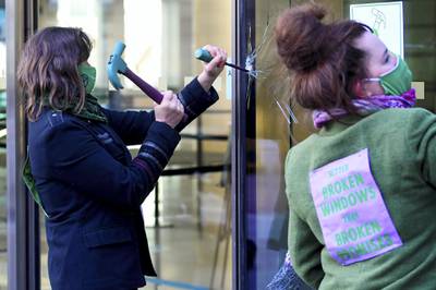 An activist from the Extinction Rebellion, a global environmental movement, damages a window during a direct action at Barclays offices in Canary Wharf, London, Britain, April 7, 2021. REUTERS/Toby Melville