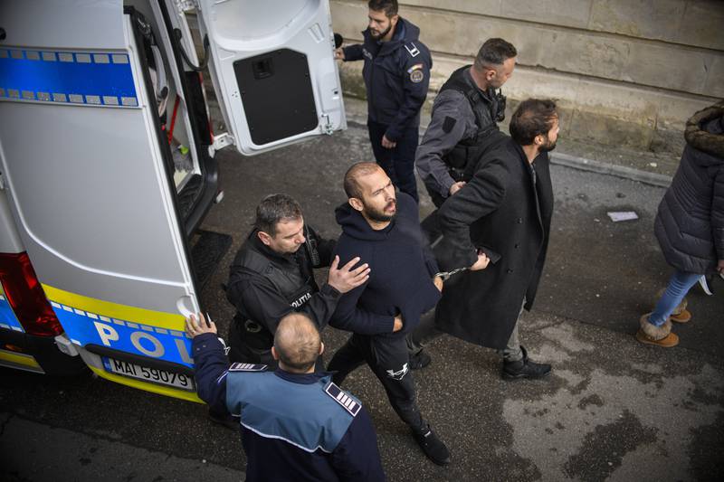 Police officers escort Andrew Tate, handcuffed to his brother Tristan, to the Court of Appeal in Bucharest, Romania. AP 