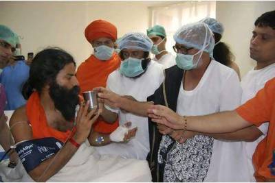 Baba Ramdev, left, is offered a glass of juice by the Hindu scholar Morari Bapu, second right, and the Indian spiritual leader Sri Sri Ravishankar, centre, as he breaks his fast at a hospital in Haridwar, India, yesterday. Patanjali Yogpeeth / AP Photo