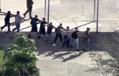 In this frame grab from video provided by WPLG-TV, students from the Marjory Stoneman Douglas High School in Parkland, Fla., evacuate the school following a shooting, Wednesday, Feb. 14, 2018. (WPLG-TV via AP)