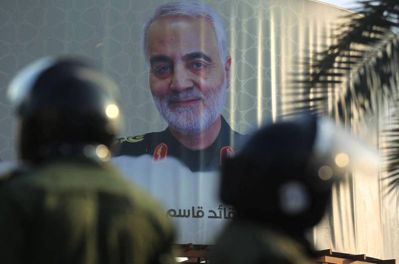 Members of the Iraqi riot police stand near a poster of Iranian commander Qasem Soleimani, who was killed in a US drone strike in Baghdad, in a square in the Iraqi capital on December 3, 2020. (Photo by AHMAD AL-RUBAYE / AFP)