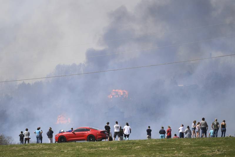 People watch as structures burn from a wildfire on Wednesday, March 30, 2022, in Sevierville, Tennessee, amid mandatory evacuations as winds whipped up beforea line of strong storms forecast to move in overnight.  Knoxville News Sentinel / AP