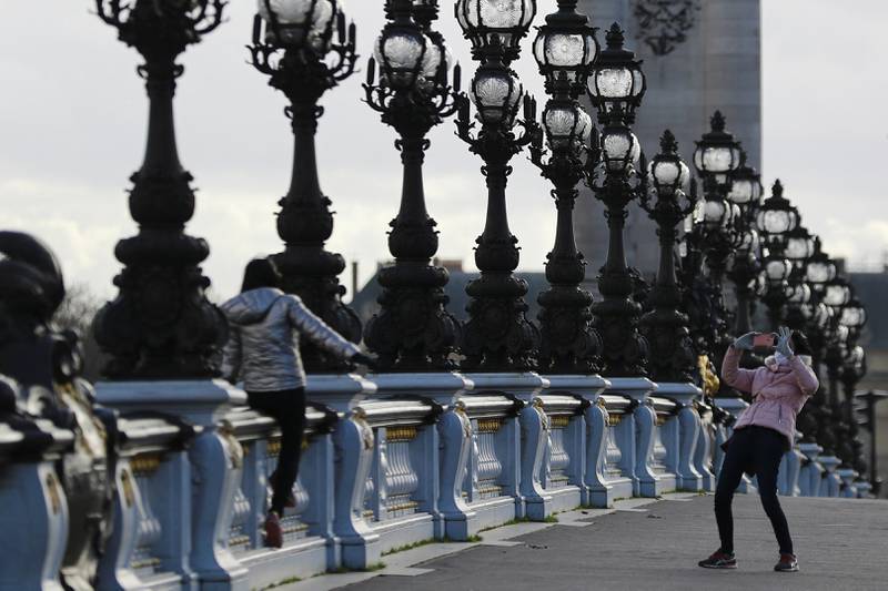 People wearing protective face masks take photographs on the Alexandre III Bridge over the River Seine in Paris. Reuters