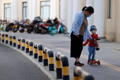 A woman and a child walk along a street in Beijing. AP Photo