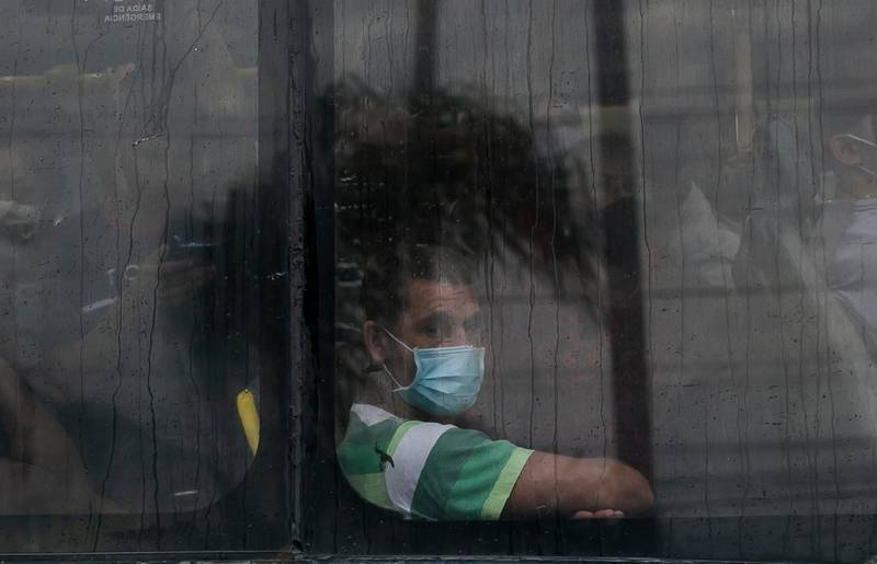 A commuter wearing a mask due to the COVID-19 pandemic peers from the window as he rides a public Rapid Transit Bus (BRT) in Rio de Janeiro, Brazil, Tuesday, March 30, 2021. (AP Photo/Bruna Prado)