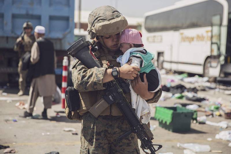 A US Marine carries a baby as the family is processed through the Evacuation Control Centre at the airport in Kabul. AFP