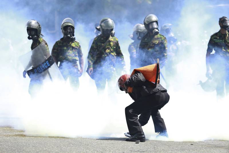 A man picks up a tear-gas canister to throw it away as police try to disperse protesters in Colombo. AP