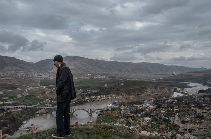Ridvan Ayhan, a 58-year-old activist who fights against the Ilisi hydroelectric dam project, looks at the "new Hasankeyf" which is seen on the other side of Tigris river, on December 13, 2018, near the historical town of Hasankeyf in Turkey's Kurdish-majority southeast. The small town of Hasankeyf, inhabited for 12,000 years, is doomed to disappear in the months ahead under an artificial lake, as a result of the dam project. The dam will be Turkey's second largest and has been built downstream of the Tigris. / AFP / BULENT KILIC
