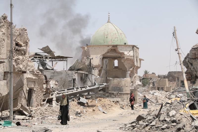 A family walks past the destroyed Al Nuri Mosque as they struggle to muster the energy to escape the old city, where heavy fighting and an intense bombardment is exacting a high toll on civilians. Florian Neuhof  / The National
