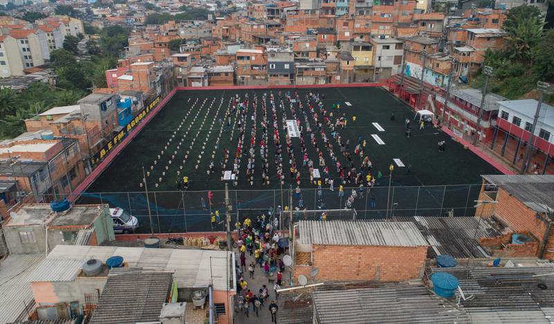 Residents wait on a soccer field for food donated by the local NGO "G10 Favelas," amid the COVID-19 pandemic in the Capao Redondo area of Sao Paulo, Brazil. AP Photo