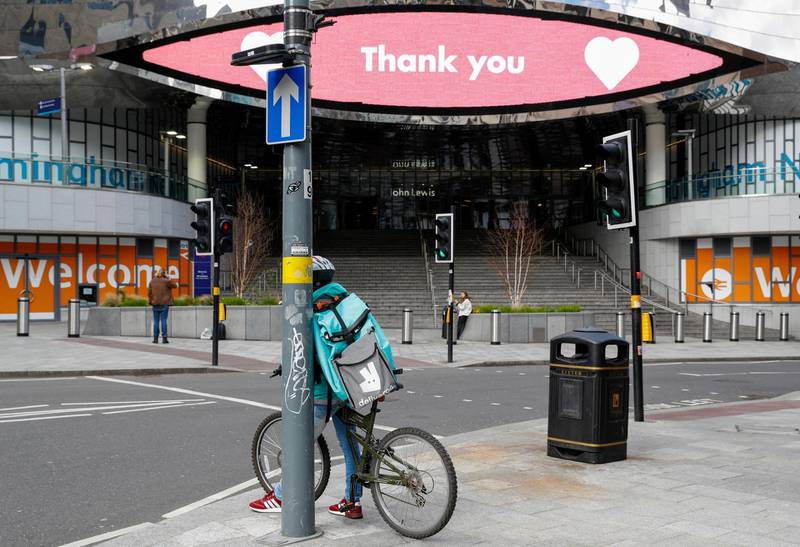 A food delivery courier carrying a Deliveroo, operated by Roofoods Ltd., backpack stands near a message thanking Britain's National Health Service in Birmingham, U.K. Bloomberg