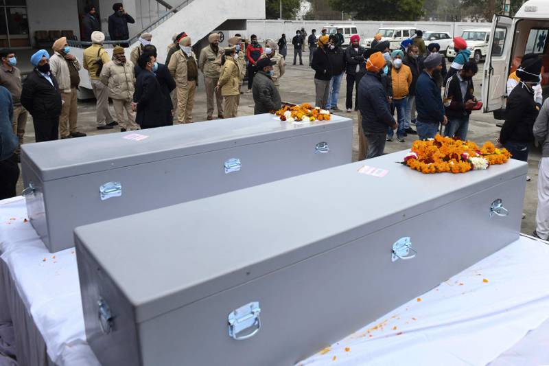 Relatives and police officials stand near the coffins of Hardev Singh and Hardeep Singh, who were killed on the January 17 Houthi attack on Abu Dhabi, at an airport on the outskirts of Amritsar in northern India.  AFP