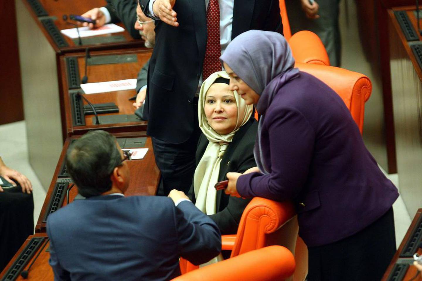 Turkey's ruling AKP MPs Nurcan Dalbudak, centre, and Sevde Beyazit Kacar, right, attend a general assembly at the parliament wearing headscarves on Thursday.  AFP 

