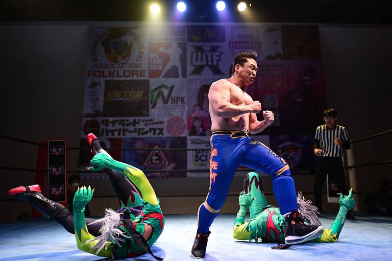 This photograph taken on July 30, 2022 shows Singaporean pro-wrestler Andrew Tang (C) aka “The Statement“ performing in the ring during a match at the SETUP Thailand Pro Wrestling show in Bangkok.  - The part-sport, part-show from SETUP Thailand Pro Wrestling has been slowly gaining popularity in Thailand, where it hopes to carve out a space for local wrestlers using distinctively Thai characters.  (Photo by Manan VATSYAYANA  /  AFP)
