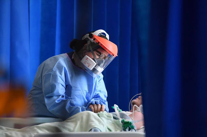 TOPSHOT - A member of the clinical staff wears personal protective equipment (PPE) as she cares for a patient at the Intensive Care unit at Royal Papworth Hospital in Cambridge, on May 5, 2020.  NHS staff wear an enhanced level of PPE in higher risk areas such as critical care to minimise the spread of infection between staff and patients. Britain's death toll from the coronavirus has topped 32,000, according to an updated official count released Tuesday, pushing the country past Italy to become the second-most impacted after the United States. / AFP / POOL / Neil HALL

