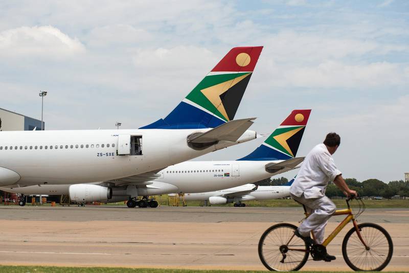 A man cycles past Airbus Group NV A340, left, and A330-200 aircraft operated by South African Airways at O.R. Tambo International airport in Johannesburg, South Africa, on Tuesday, Feb. 24, 2015. South African Airways is close to a 1.25 billion-rand ($107 million) savings target after renegotiating airline leases and supply contracts, canceling two long-haul destinations and reviewing the route of Washington D.C. flights. Photographer: Waldo Swiegers/Bloomberg