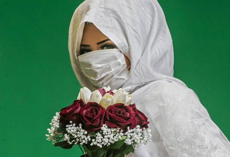 A Palestinian bride, wearing a protective mask, poses for pictures at a local studio before her wedding ceremony, in Khan Yunis in the southern Gaza Strip.  AFP
