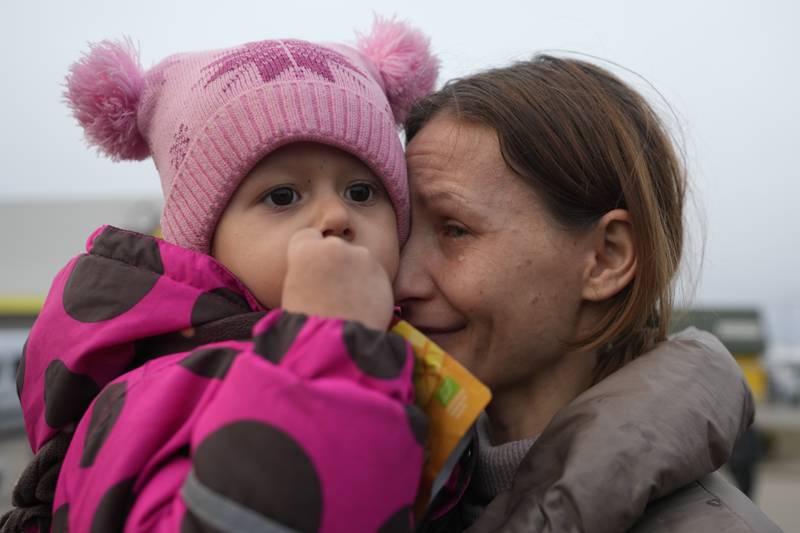 A woman with a child who fled from the war in Ukraine reunite with their family after crossing the border in Medyka, Poland. AP