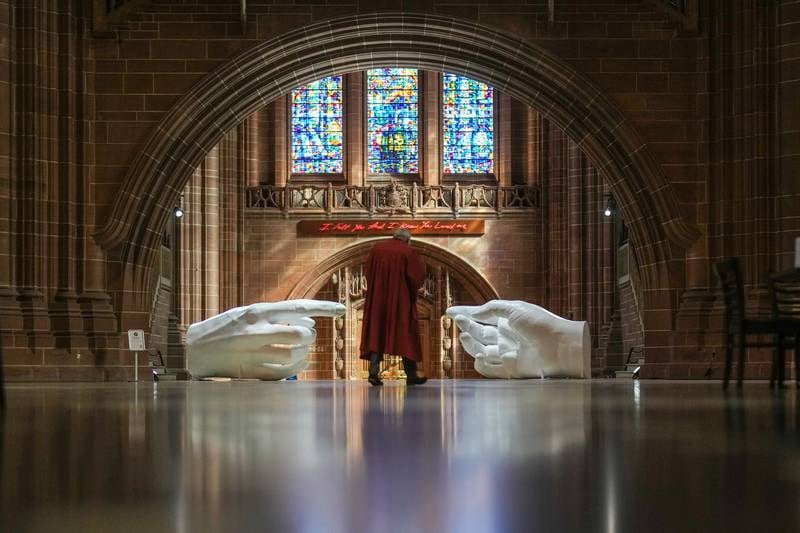 Giant hands reach across Liverpool Cathedral on Wednesday, as part of artist Peter Walker's latest exhibition Being Human in the north-western city. Getty Images
