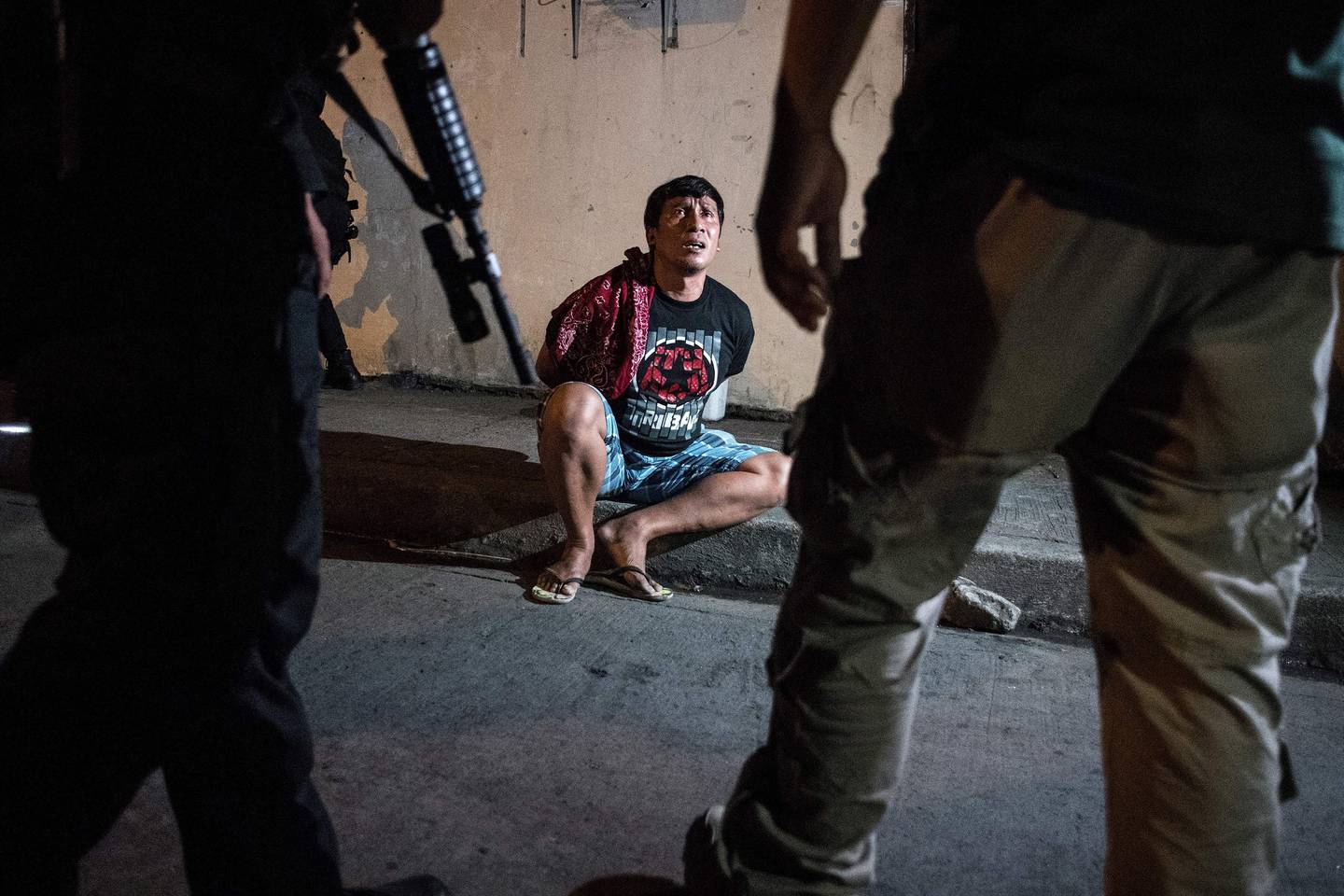 Philippine Drug Enforcement Agency officers and policemen arrest a man suspected of dealing in drugs during a drug raid in Maharlika Village, Taguig, south of Manila, in 2018. AFP