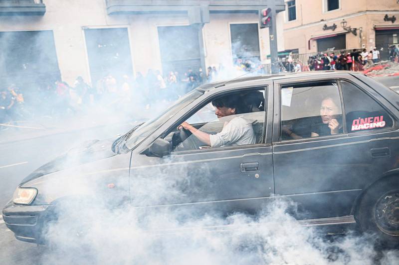 Residents take cover from tear gas thrown by the police during clashes in Lima. AFP
