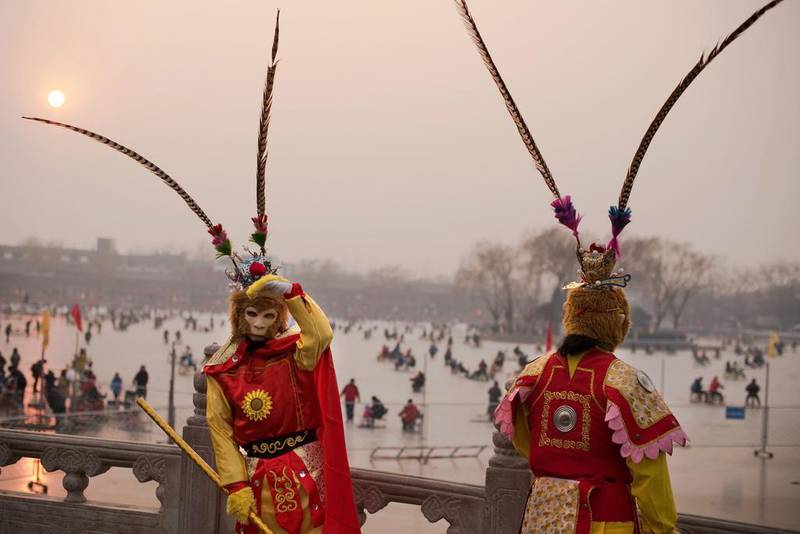 Actors dressed up as monkeys stand on a bridge next to the frozen Houhai lake in Beijing ahead of the Lunar New Year. Nicolas Asfouri / AFP Photo