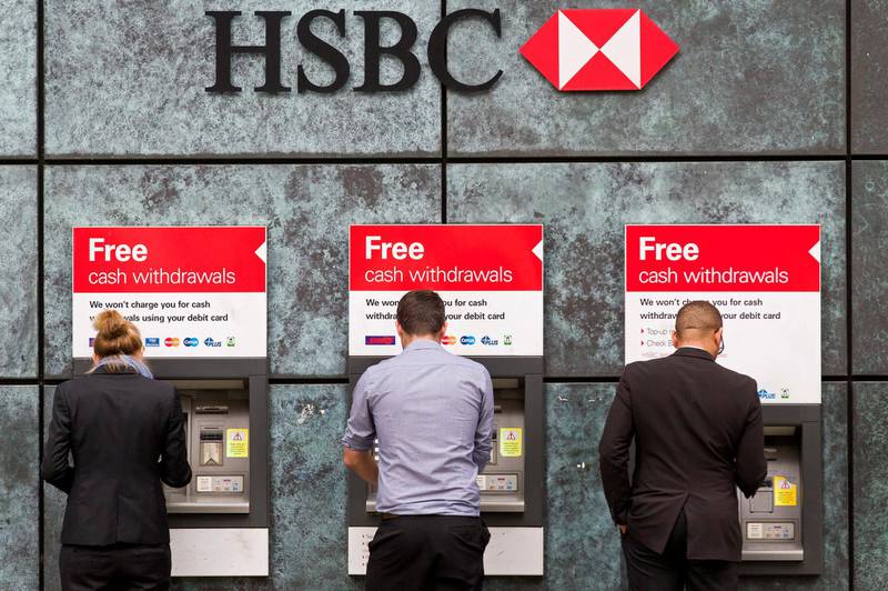 Customers use ATM cashpoints outside a HSBC bank branch in London on June 9, 2015. Scandal-hit bank HSBC said it would cut its global headcount by up to 50,000 as part of a restructuring that entails its withdrawal from Brazil and Turkey, while it also mulls abandoning London as its HQ.   AFP PHOTO / JUSTIN TALLIS (Photo by JUSTIN TALLIS / AFP)