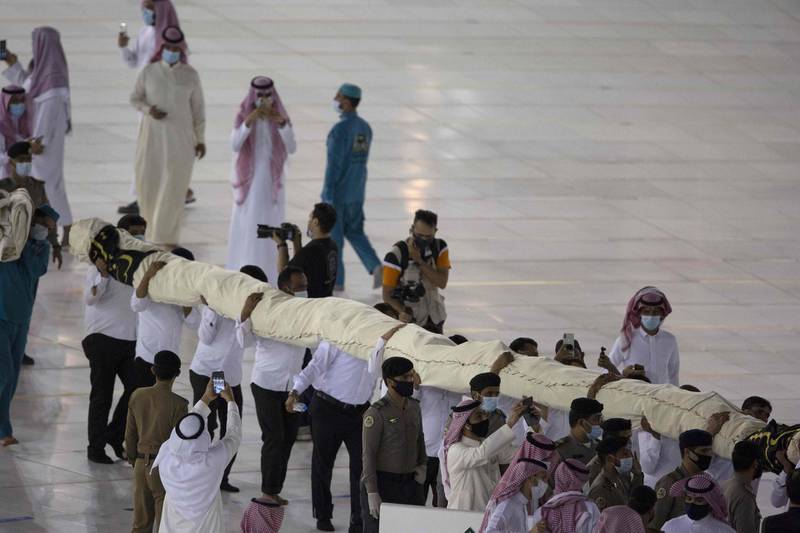 Saudi labourers carry the new Kiswa, the protective cover that engulfs the Kaaba, made from black silk and gold thread and embroidered with Koran verses in Saudi Arabia's holy city of Mecca.  AFP