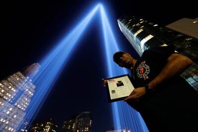 Sergeant Edwin Morales holds a photo of his cousin, Rubin Correa from Engine 74, by the Tribute in Light installation in New York. Reuters