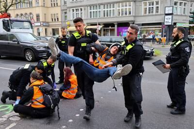 Police officers carry away an activist of the Last Generation climate group who glued himself to a street in the Steglitz district of Berlin. Reuters