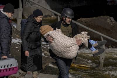 A man carries an elderly woman as people continue to leave Irpin. AP