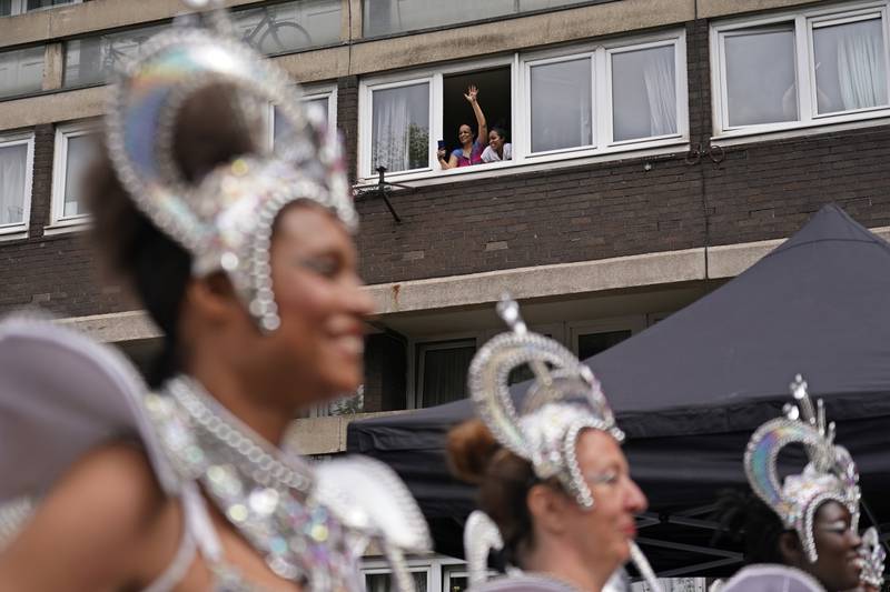 A woman waves from a window as performers take part in the carnival. AP