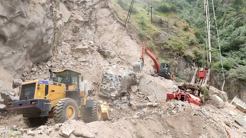 In this handout photograph provided by the Jammu and Kashmir Government's Department of Disaster Management, earthmovers work to clear the site where an under construction tunnel collapsed in Ramban district, in Indian-controlled Kashmir, Friday, May 20, 2022.  An official said Friday that 10 workers were trapped after part of an under construction road tunnel collapsed in the Himalayan region.  (Jammu and Kashmir Government's Department of Disaster Management via AP)
