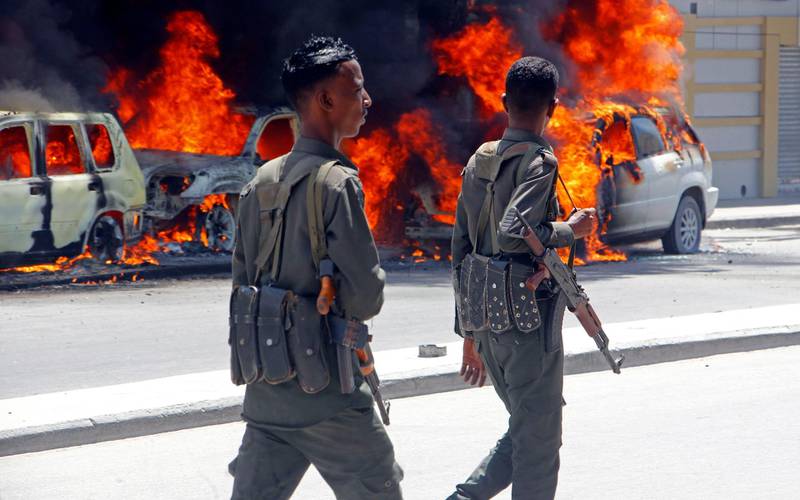 Soldiers walk past cars burning after car bomb detonated in Mogadishu, Somalia, Wednesday, April 17, 2019. (AP Photo/Farah Abdi Warsameh)