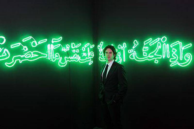 Nick Hackworth, the owner of the London gallery Paradise Row, with a Quranic verse in neon calligraphy by Shezad Dawood, on display at the  Abu Dhabi Art fair at the Emirates Palace hotel.