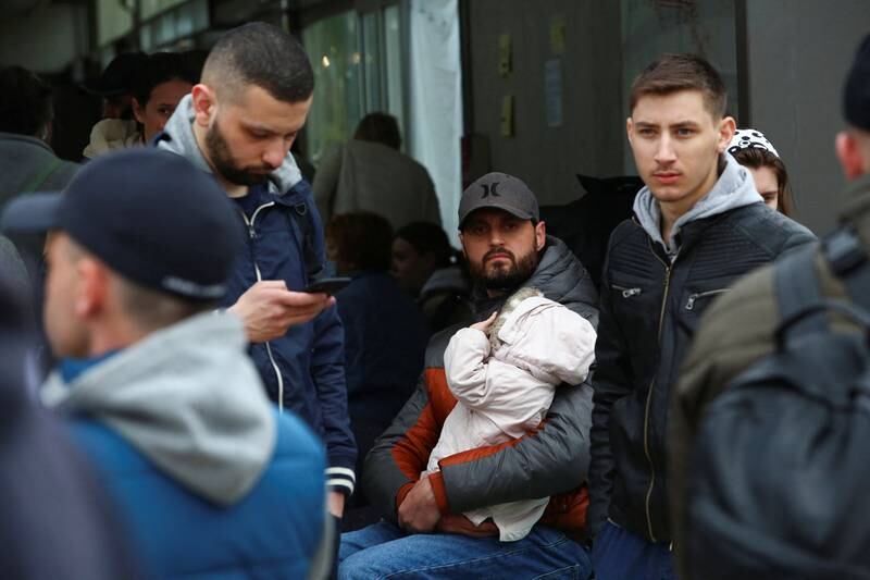 A Ukrainian man holds a baby at US-Mexican border as he waits to cross into the US. Reuters