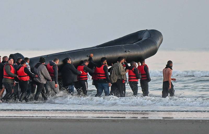 Migrants hold up an inflatable boat before attempting to cross the Channel to Britain, near the northern French city of Gravelines, in July. AFP