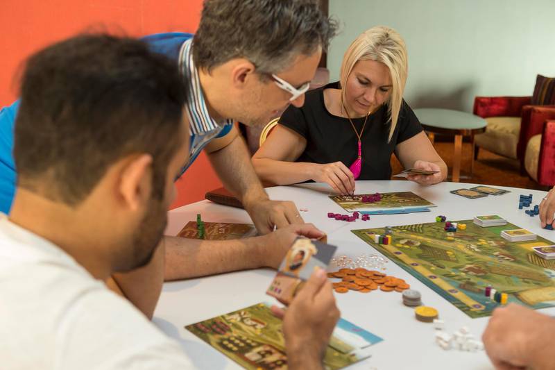 DUBAI, UNITED ARAB EMIRATES, 21 JUNE 2016. Members of the Table Top Cafe meet at the Sky Lounge in Gloria Hotel, Media City. Table Top Cafe is a new tabletop gaming community set up in Dubai to promote gatherings over board games. The members meet up several times a month in different cafes and restaurants to play games like Chess, Mahjong, Dungeons and Dragons, socialise, learn new games and hold competitions. LtoR: Awab AlShwaikh (Iraq), Filippo Cipriani (Italy), Agnes Koltay (Hungary) (Photo: Antonie Robertson/The National) ID: 17281. Journalist: Afshan Ahmed. Section: National. *** Local Caption ***  AR_2106_Table_Top_Cafe-07.JPG