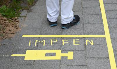 An employee of the chemical and pharmaceutical company Merck KGaA stands at a ground marker with the word 'Vaccinate' and a syringe on the factory premises in Darmstadt, Germany. EPA