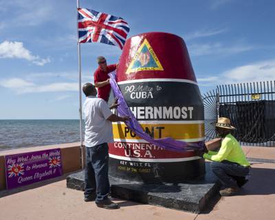 Key West Community Services staff members position a purple sash around the Southernmost Point marker in tribute to Queen Elizabeth in Key West, Florida. AP