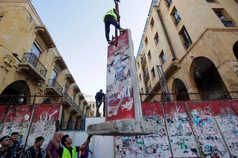 Workers remove sections of the concrete barrier, which was erected by Lebanese security forces in 2020 to bar access to streets leading to the country's parliament building, at the entrance of the Lebanese Parliament in the capital Beirut. AFP