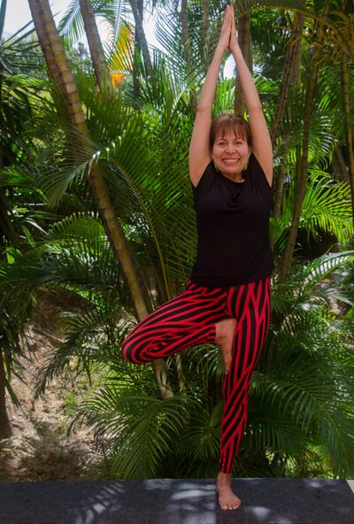 Yoga instructor executes the Vrksasana yoga position at the tropical garden