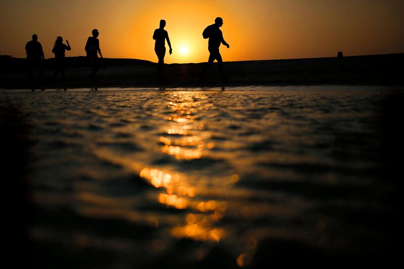 FILE - In this file picture taken Thursday, Aug. 20, 2015, tourists walk on the Giftun Island beach as the sun sets over the Red Sea in Hurghada, Egypt. Egypt's Interior Ministry said Friday, July 14, 2017 six foreign tourists, of various nationalities, were wounded when a man attacked them with a knife in the Red Sea resort of Hurghada. The ministry says the assailant was arrested immediately after the stabbings on Friday. It says the initial investigation shows the man sneaked into a hotel by swimming from a nearby beach and stabbed the tourists. (AP Photo/Hassan Ammar, File)