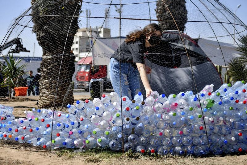 A Tunisian protester piles empty plastic bottles during a demonstration to demand the return to Italy of household waste exported Illegally to the country, in the Mediterranean port city of Sousse, on March 28, 2021. AFP