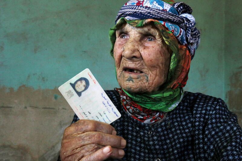 Heimish holds up her ID card. Her year of birth is stated as 1901, indicating she is about 120 years old. She says that, like many people at the time, she received a formal identity document only when she turned 18. A neighbour whose own official record of birth confirms he is a centenarian can recall Heimish as a young woman and that she held him when he was a baby.